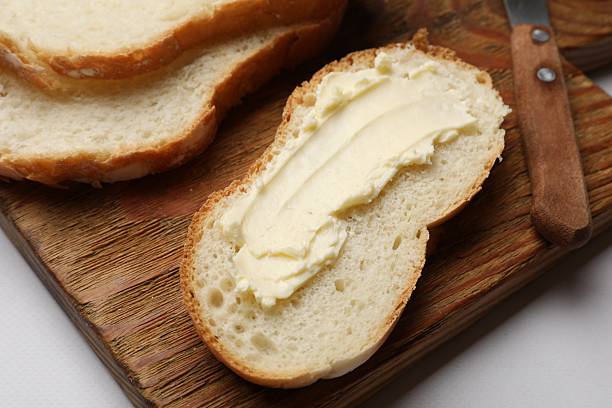 istock Slice of fresh bread with butter on white table, closeup 2227347762