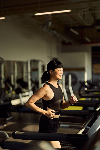istock Smiling Woman Jogging on a Treadmill in a Modern Gym Setting 2227350004