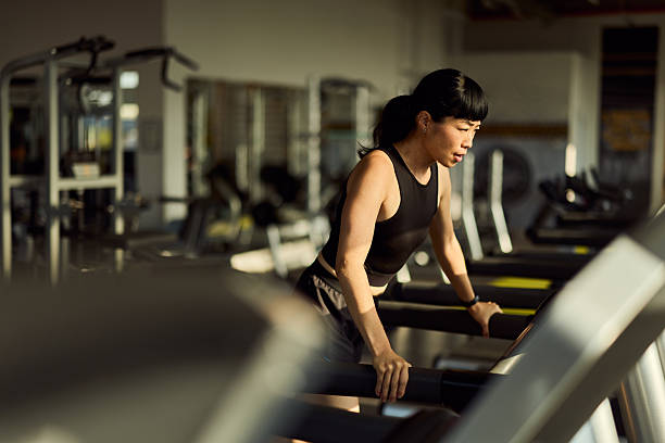 istock Focused Woman Exercising on a Treadmill in a Bright Modern Gym Setting 2227350007