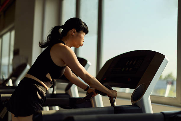 istock Woman Exercising on Treadmill in a Brightly Lit Modern Gym Environment 2227350025