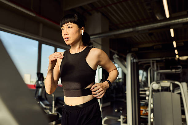 istock Woman Running on a Treadmill in a Gym Setting with Determined Expression 2227350030