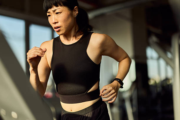 istock Focused Woman Running on Treadmill in Modern Gym During Workout 2227350059