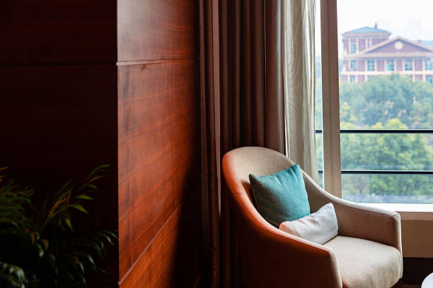 istock Fabric sofa placed by the window with flower arrangement on the side 2227350479