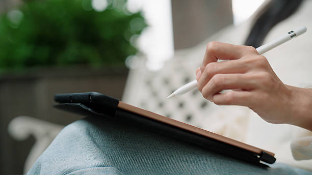 istock Asian woman taking notes on her digital device while sitting comfortably on a park bench 2227351163