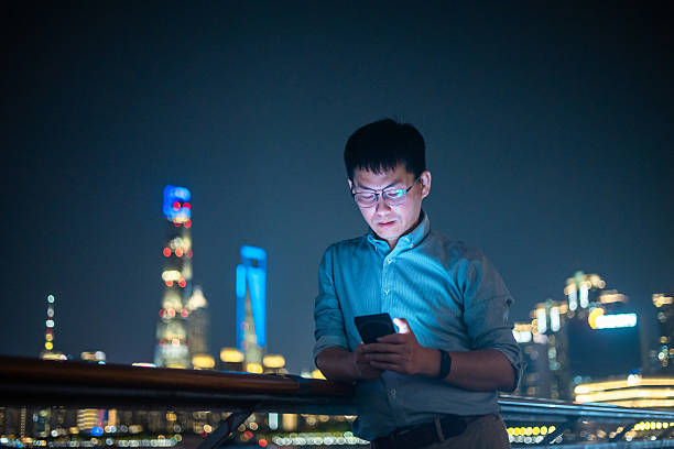 istock Confident male executive using mobile phone in Shanghai's financial district at night 2227351490
