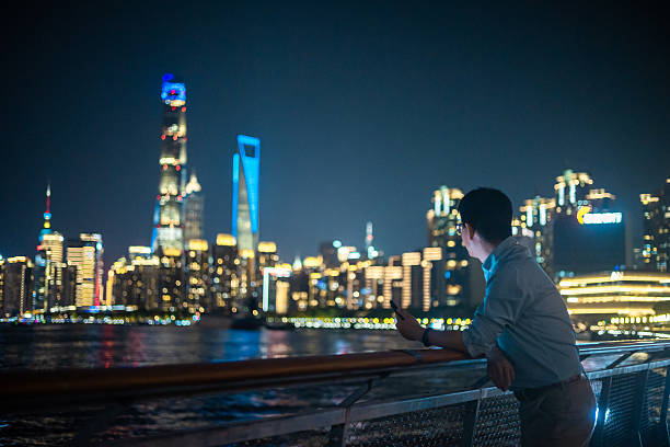 Confident male executive using mobile phone in Shanghai's financial district at night