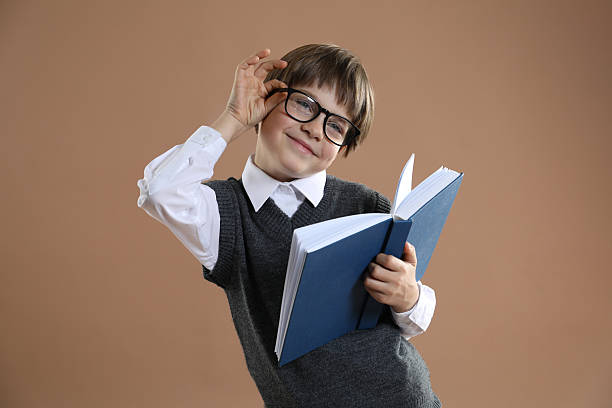 istock Learning alphabet. Little boy with book on brown background 2227354414