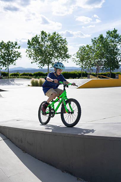 istock Young boy riding a bicycle on a concrete ramp in a skate park 2227355279
