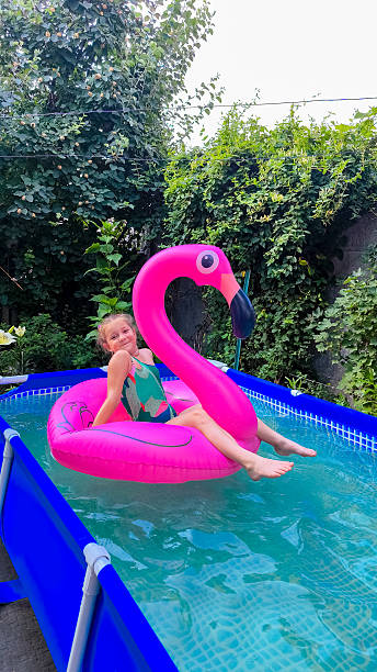 istock Girl relaxing on pink flamingo float in backyard pool 2227357978