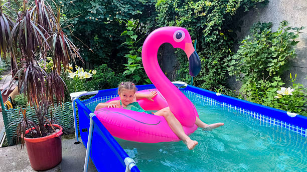 istock Girl relaxing on pink flamingo float in backyard pool 2227357981