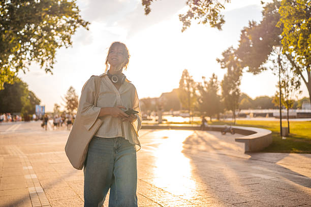 istock Young Woman Using Phone While Walking In The Public Park 2227358107