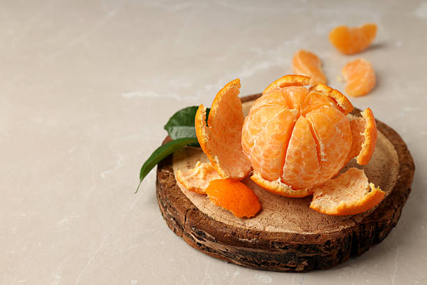 istock Board with mandarin and leaves on light textured background 2227360461