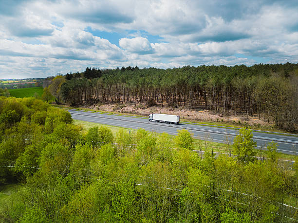 White unbranded truck driving on highway in forest, logistics delivery