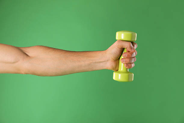 istock Man exercising with dumbbell on green background, closeup 2227362296