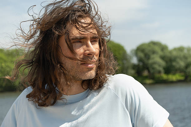 Man skyward in sunglasses against cloudy blue sky at summer.