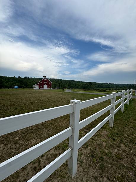 Red barn behind white fence in rural Maine