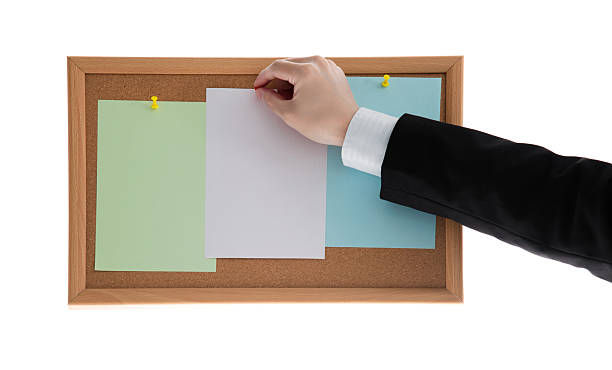 istock Businessman hands pin sticky notes on cork bulletin board against white background 2227371136