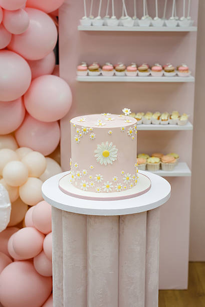 istock A beautiful pink birthday cake elegantly decorated with sugar daisies, serving as the centerpiece of a festive dessert table for a girl's party or baby shower 2227375636
