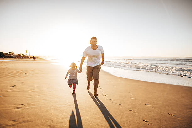 istock dad help to walk the little daughter at the beach 2227378919