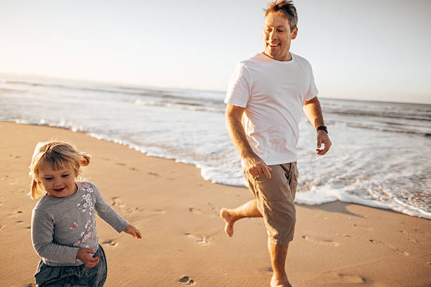 istock dad help to walk the little daughter at the beach 2227379863
