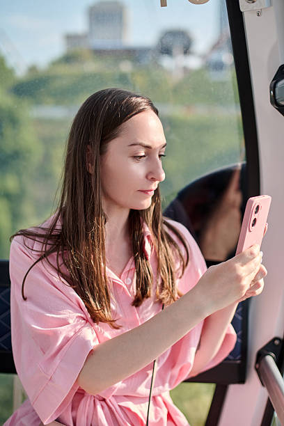 istock Young woman using smartphone in sunlit gondola 2227383111