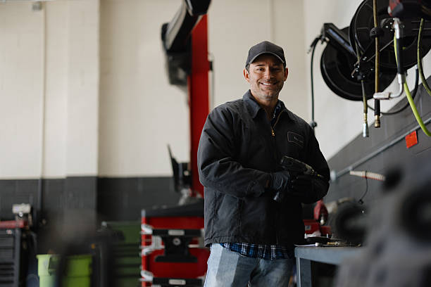 istock Mechanic holding a pneumatic wrench and smiling at camera in a workshop 2227385861