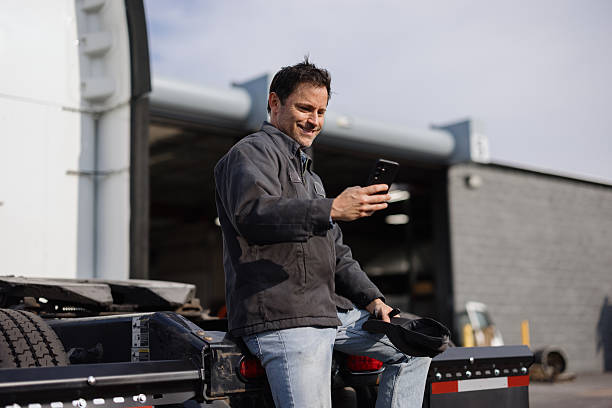 istock Truck driver using smartphone app sitting on semi truck trailer 2227385906