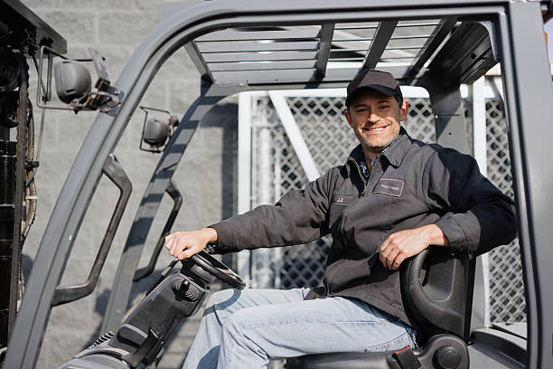 Smiling warehouse worker driving a forklift, showcasing professionalism and skill in an industrial setting during daytime operations