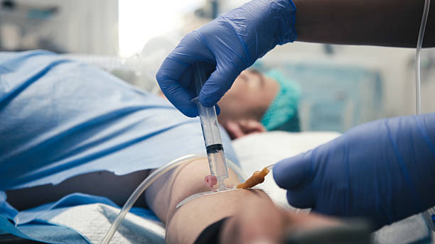 istock Medication in a syringe being injected into an IV catheter during surgery. 2227387355