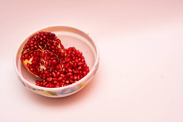 Fresh organic red pomegranates in a bowl on a white background, symbolizing health, nutrition, purity, and natural fruit freshness for diet, wellness, and culinary use.