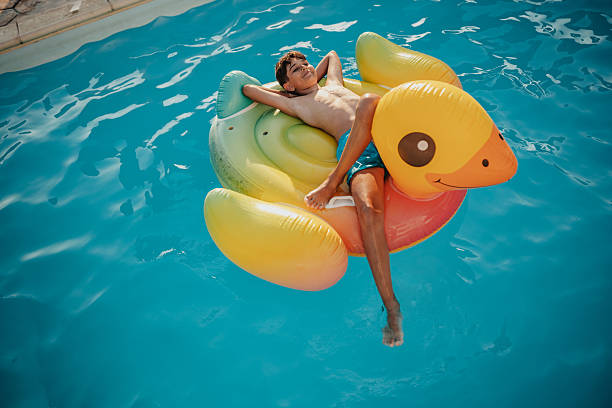 istock Young boy enjoys summer fun while relaxing on a colorful pool float in the backyard swimming pool 2227390593