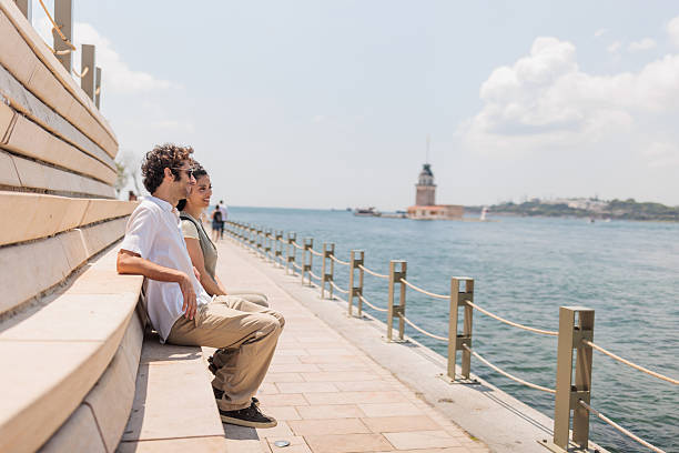 Couple sitting along the picturesque Istanbul waterfront, enjoying the tranquil views of the Bosphorus Strait and the vibrant cityscape that stretches beyond.