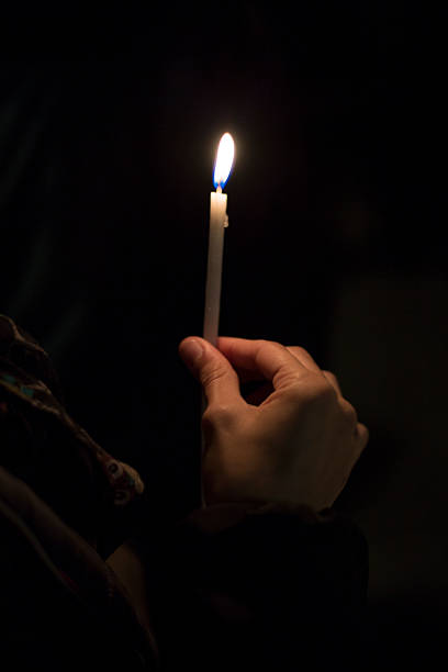 istock A person is holding a lit candle in their hand while standing in the dark 2227395751