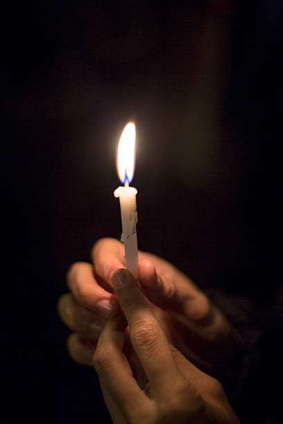 istock A person is gently holding a lit candle in their hands while in the dark 2227396512