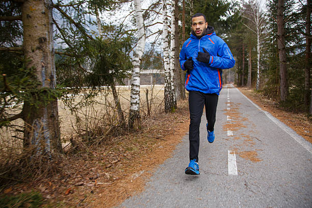 istock Dynamic African-American Male Runner in Blue Jacket on Forest Road 2227396538
