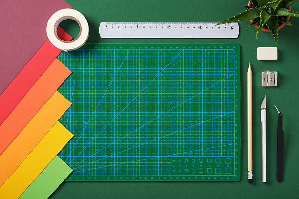 istock Crafting tools and colored paper on green background with empty cutting mat. DIY, hobby, scrapbooking and creative project preparation. 2227399741