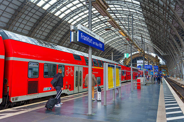 Frankfurt, Germany - June 10, 2025: Train platform at Frankfurt Hauptbahnhof featuring a red regional train and passengers, showcasing modern architecture and vibrant colors under bright daylight.