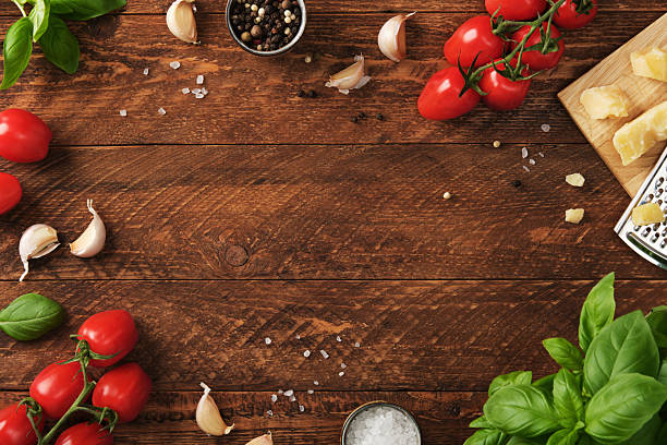 istock Fresh Italian ingredients including cherry tomatoes, garlic, basil, cheese, salt, and pepper arranged on rustic wooden table. 2227400603