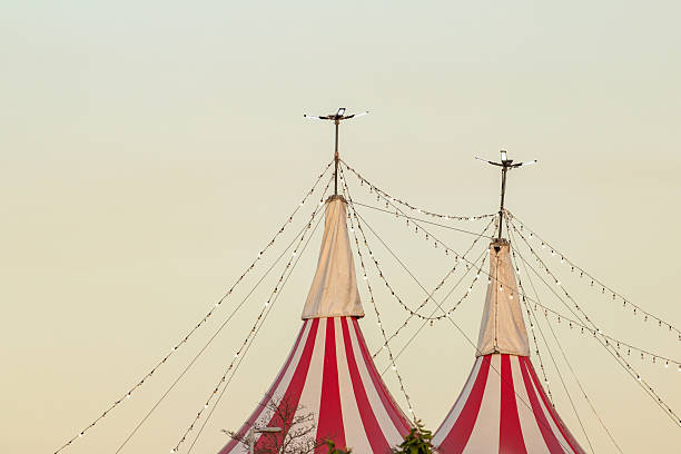 Goiania, Goias, Brazil – June 25, 2025: Top of a circus structure, with red and white striped tents and strings of lights lit up, at dusk.