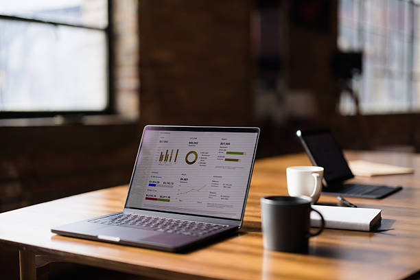 istock Laptop displaying financial charts and data analysis on a wooden table in a modern office 2227404331