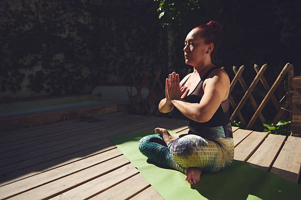 istock Woman Practicing Yoga Outdoors in Meditative Pose on Wooden Deck 2227404555