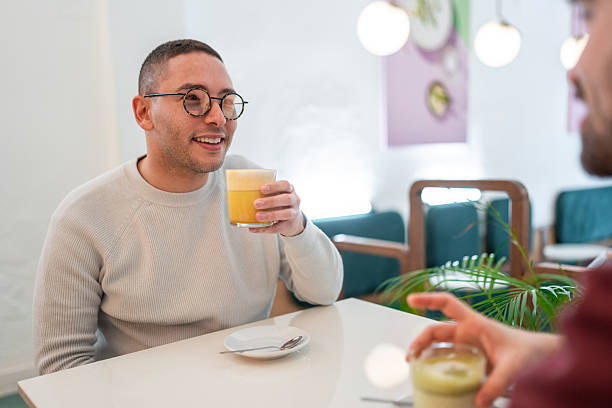 istock Young Hispanic Gay Couple Sharing Drinks in a Cozy Bistro Setting 2227404901