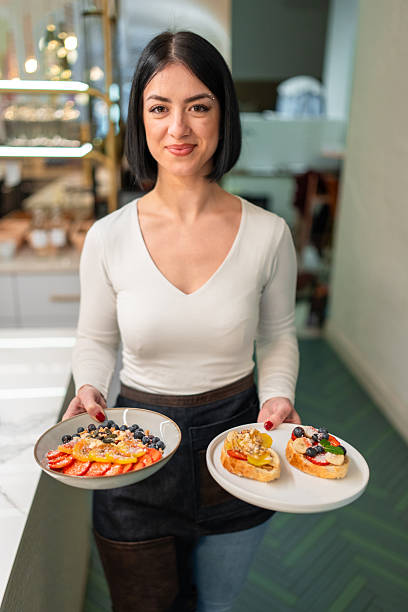 istock Friendly Young Waitress Serving Fresh Brunch Plates in a Cozy Bistro 2227404937