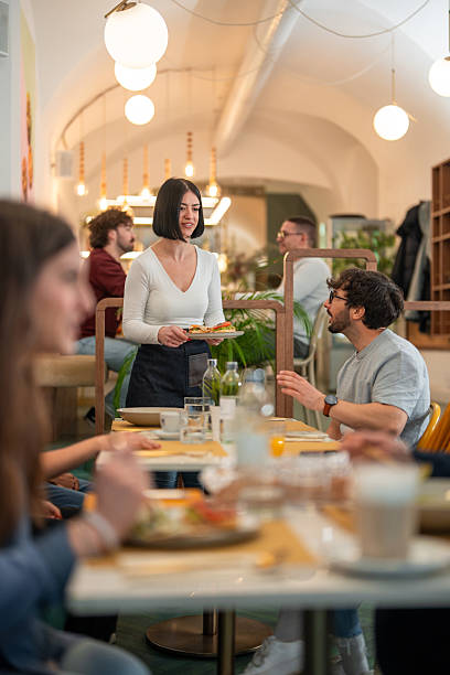 istock Professional Waitress Taking Order From Customers At Trendy Restaurant With Arched Ceilings 2227404973