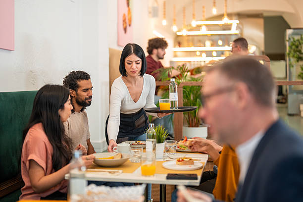 istock Friendly Waitress Serving Brunch to Diverse Friends in a Cozy Bistro Setting 2227404992