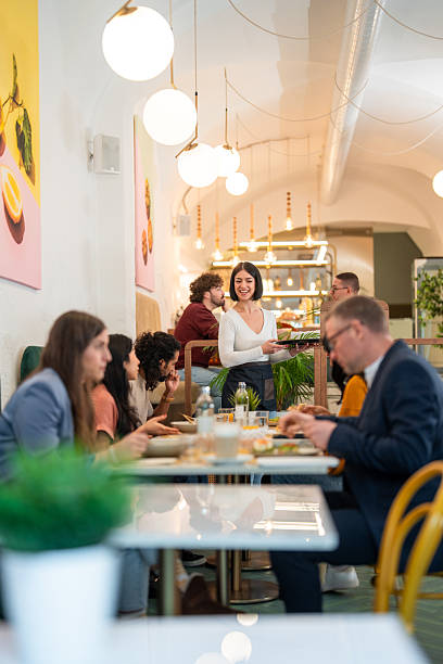 istock Friendly Waitress Serving Diverse Friends in a Cozy Bistro with Warm Lighting 2227404993