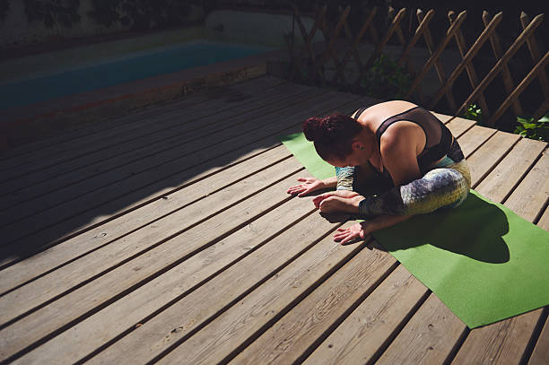 istock Woman Practicing Yoga Outdoors on a Wooden Deck in Natural Light 2227405091