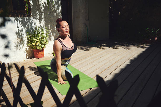 Woman Practicing Yoga Outdoors on a Wooden Deck on a Bright Day
