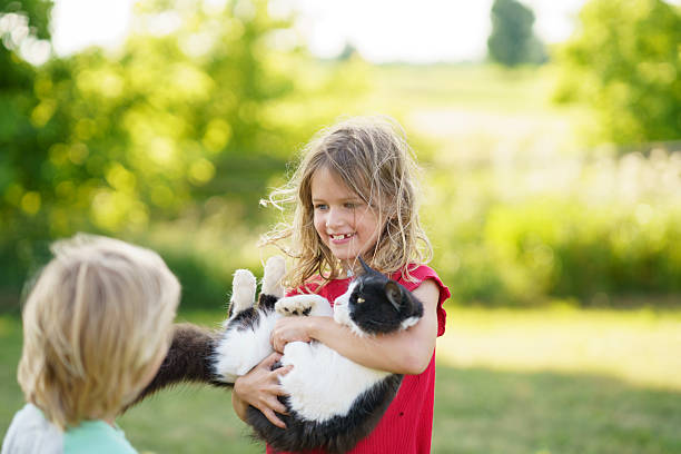 Portrait of child girl playing with ginger cat in spring backyard garden
