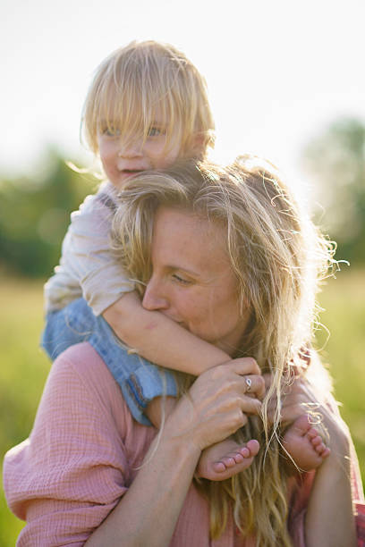 istock Mother Holding Child Outdoors in Warm Sunlight During a Summer Day 2227407498